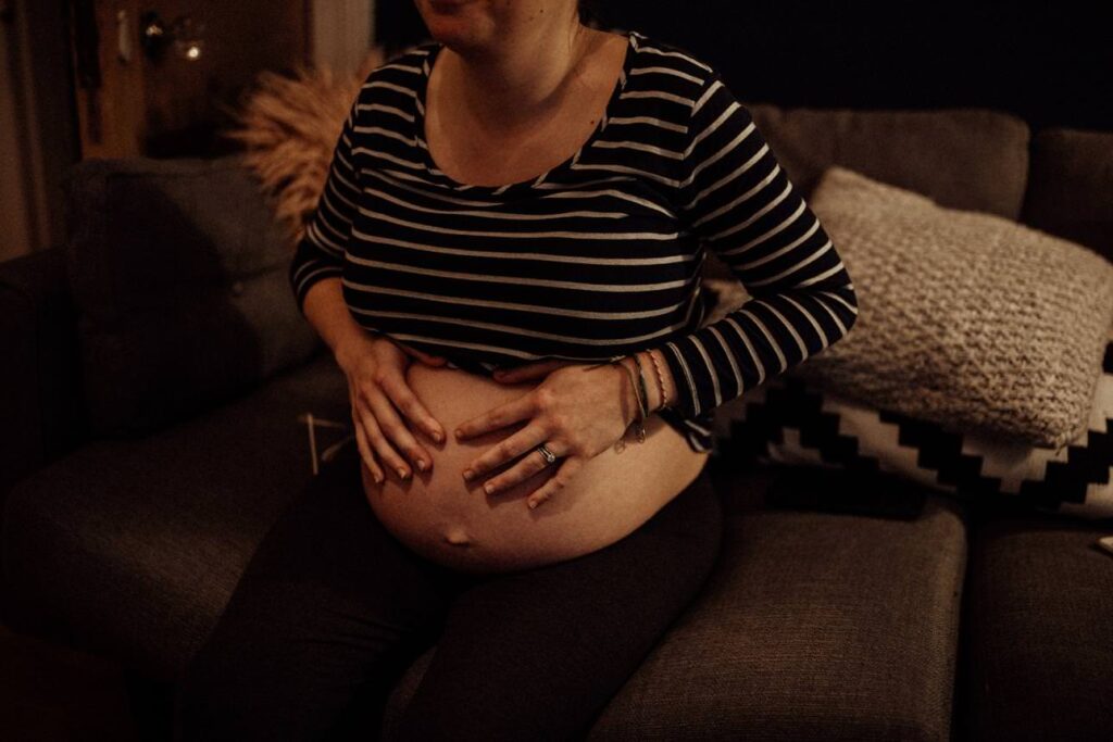 mother with hands resting on her bump while she labours at home.