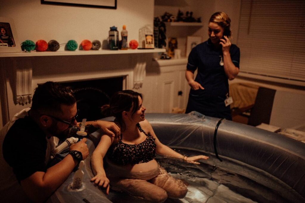 a lighthearted moment during an intimate home birth as midwife phones for the second midwife to arrive.