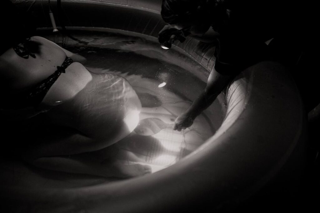 Quiet home birth scene with birthing pool, low light, and a peaceful atmosphere.