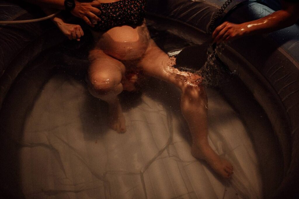 Documentary birth photography showing raw emotion during a home water birth.
