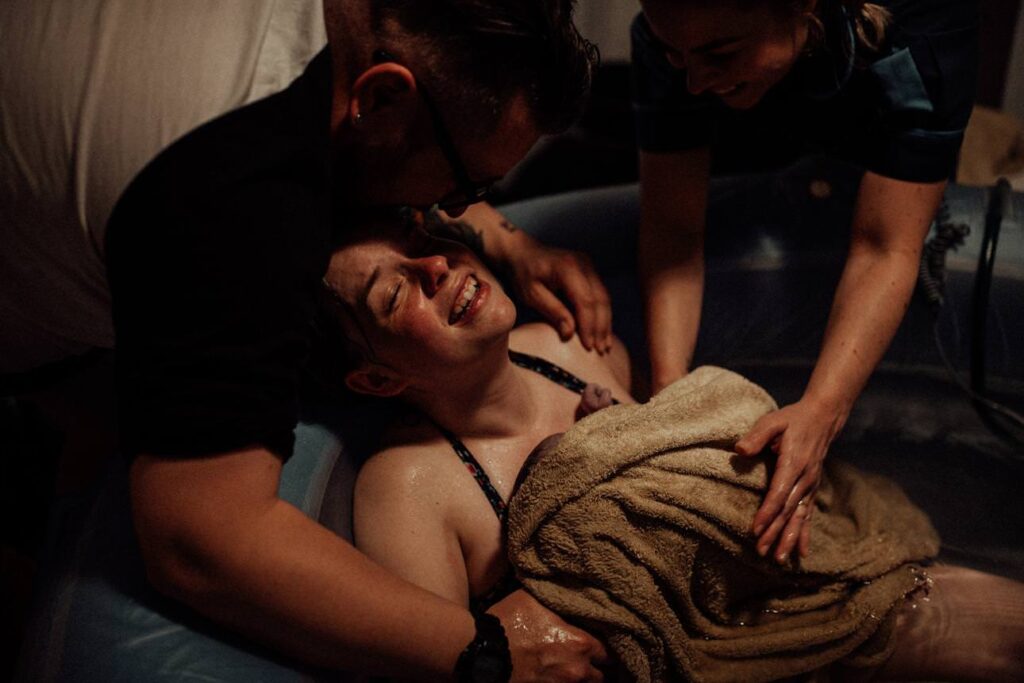 Emotional moment as parents cradle their newborn following a home water birth.