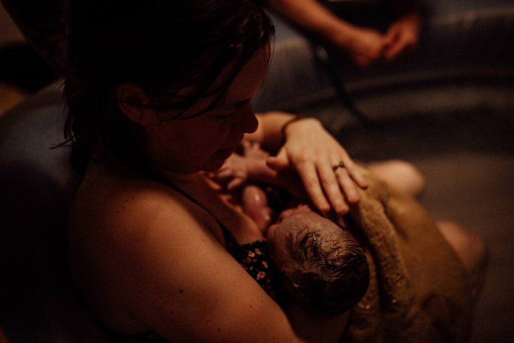 First moments after birth in the water, parents meeting their baby skin-to-skin.