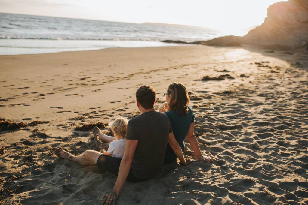 Family sitting on the beach looking out to sea
