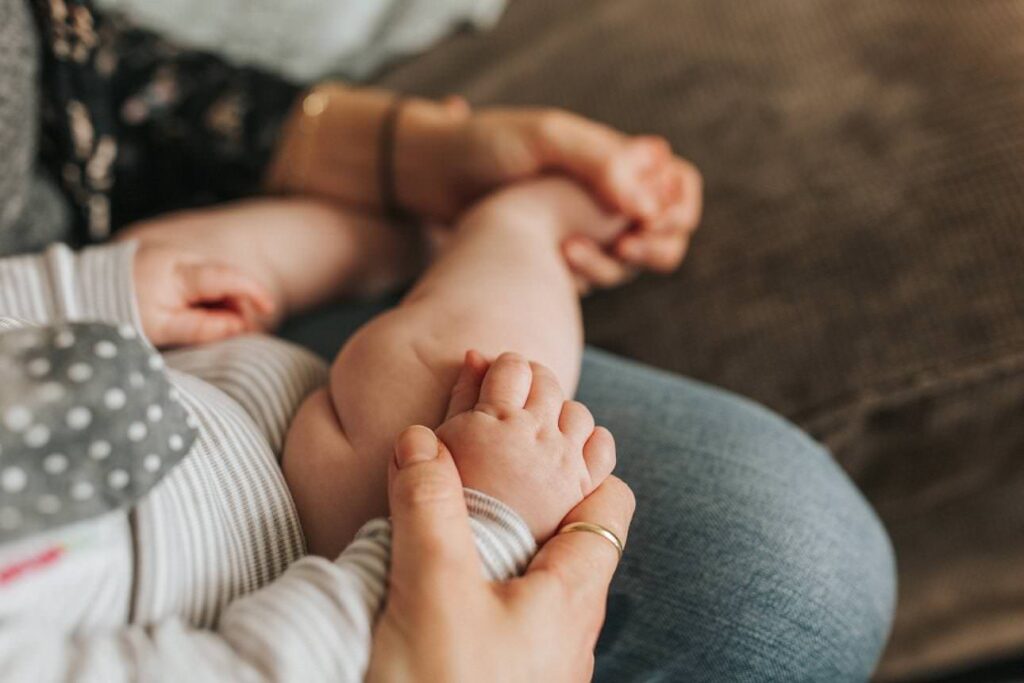 detail image of a mother holding her baby's hand in her home in Plymouth during an intimate motherhood session