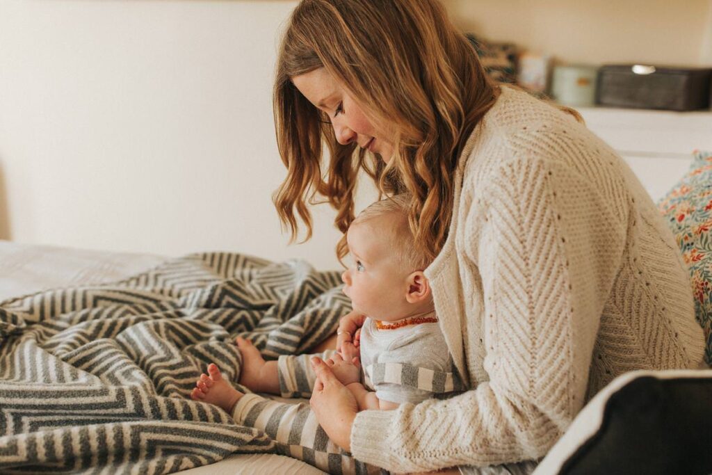 a mother cuddling her baby son in their light-filled home in plymouth