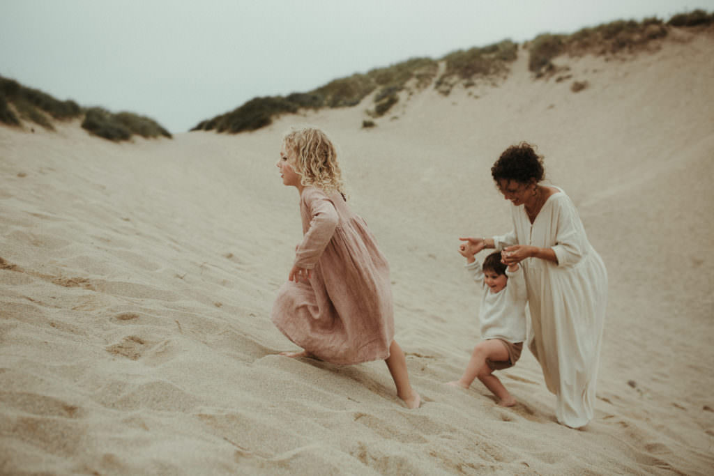 mother and two children climbing up the sand dunes during lifestyle family photography session