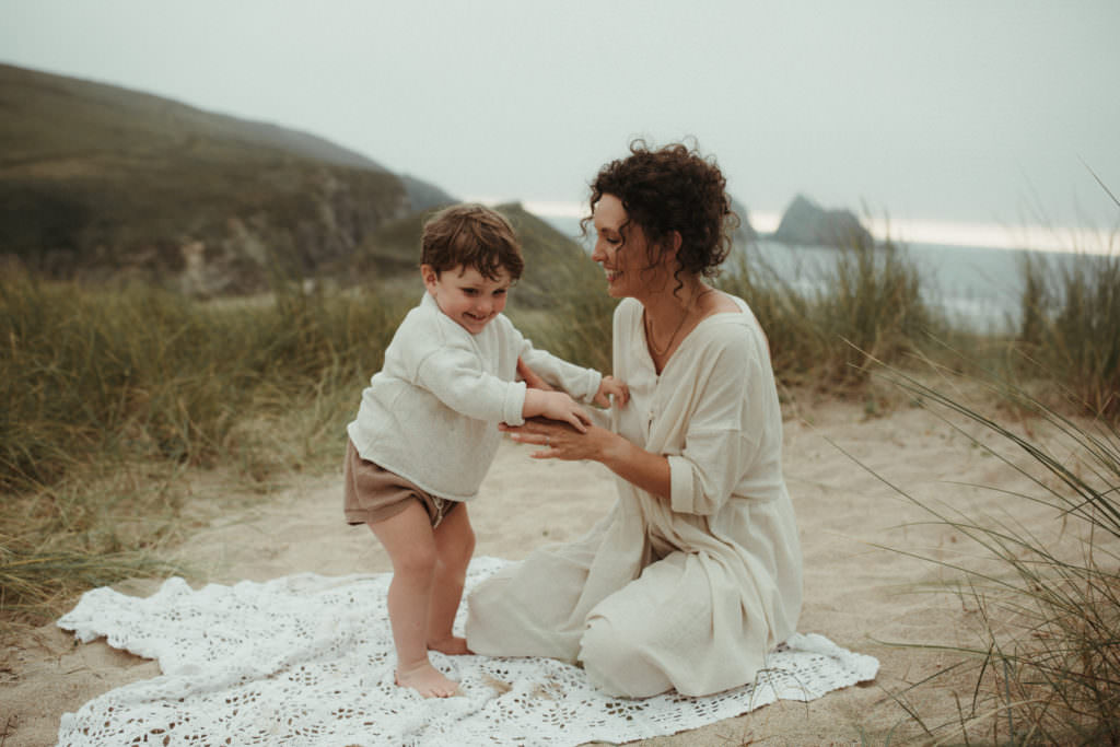 mother plays with son on blanket in the sand dunes during ifestyle family photography session
