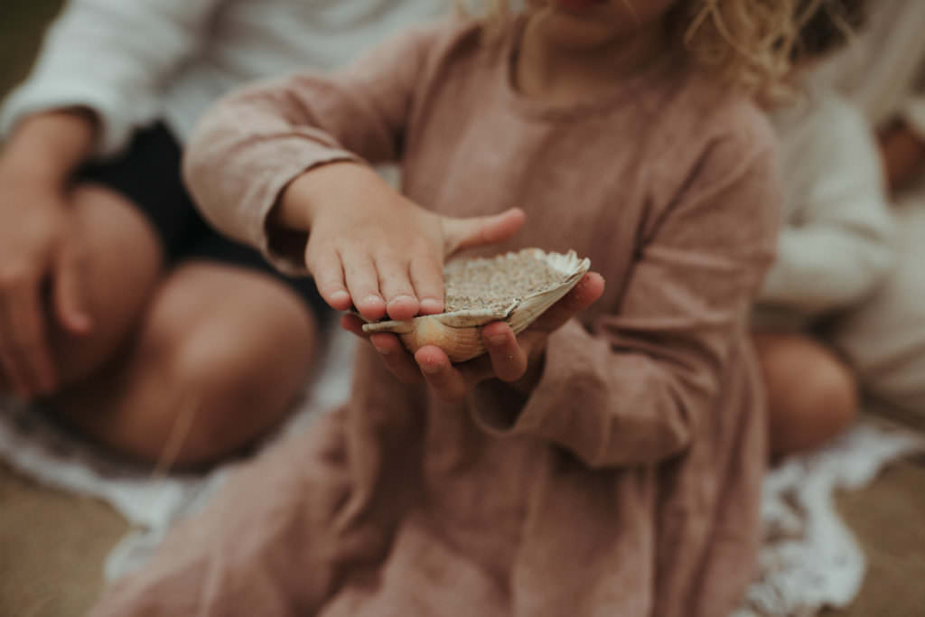 close up shot of little girl playing with a shell during lifestyle family photography session