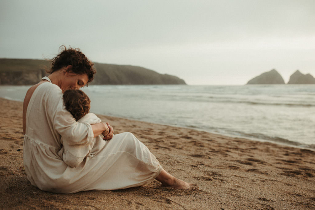 mother breastfeeds toddler whilst looking out to sea