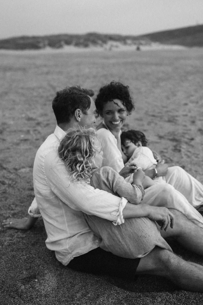 black and white shot lifestyle family photography family laughing whilst toddler nurses
