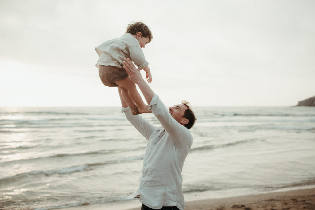 lifestyle family photography dad throws son up in the air whilst both laugh