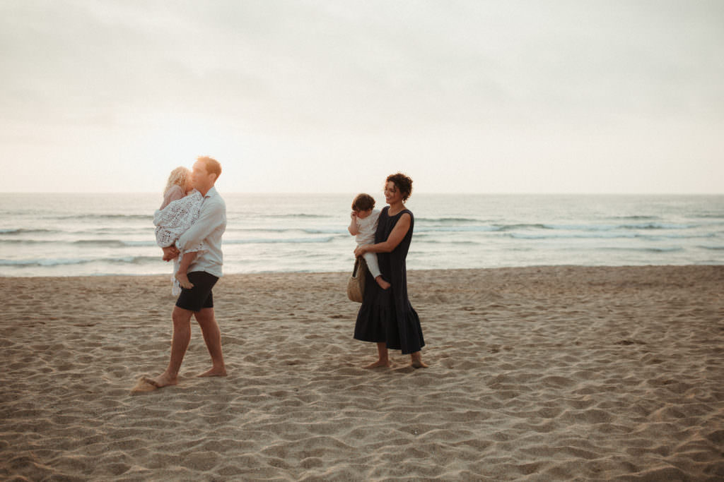 lifestyle family photography walking couple carrying a child each on sandy beach at sunset