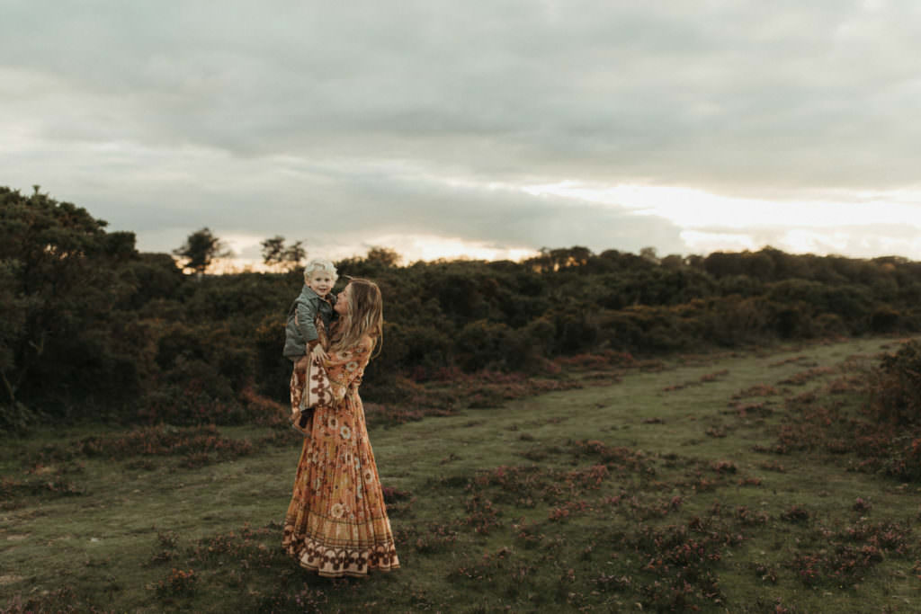 family photographer devon shoot Mum holds son up with beautiful scenery of Dartmoor National Park behind