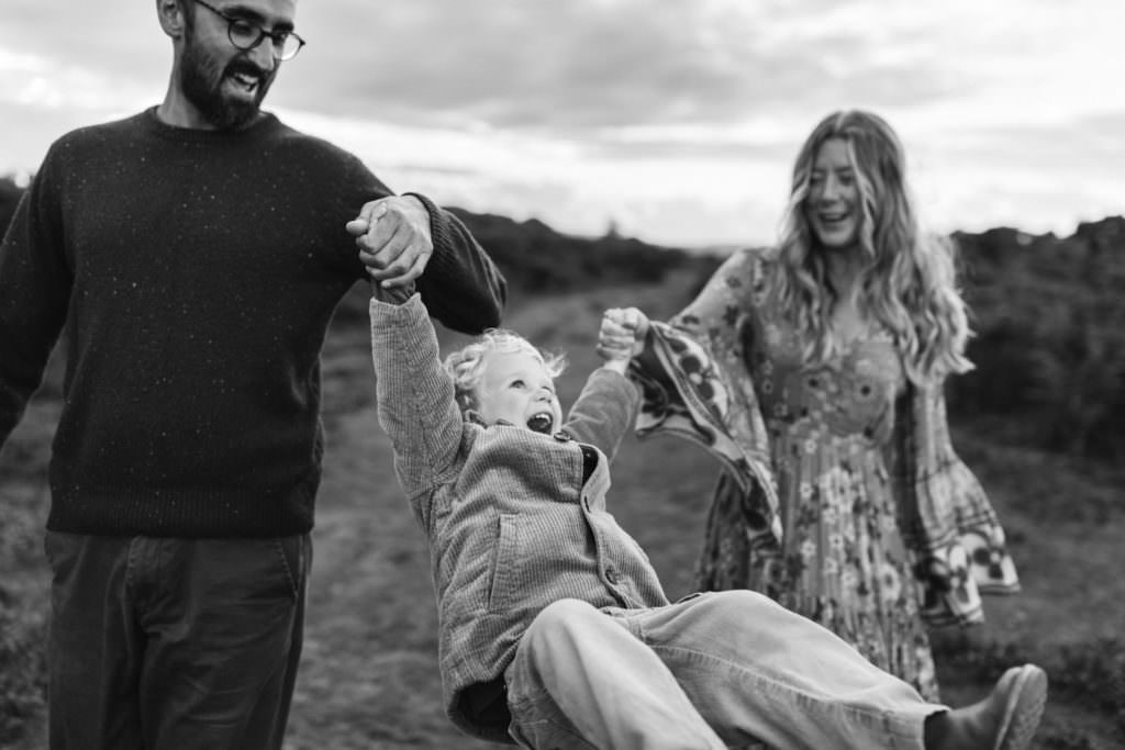 family photographer devon shoot black and white images of mum and Dad swinging son
