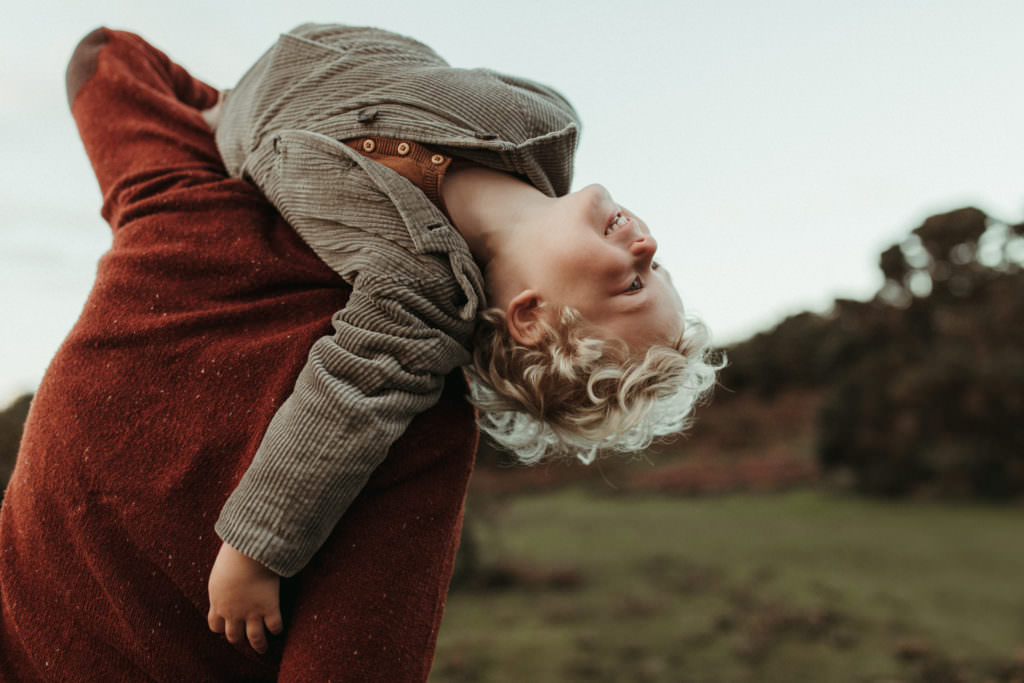 family photographer devon shoot Dad holds son over shoulder and boy leans back with a smile