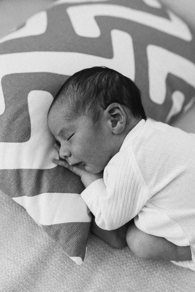 Newborn baby cuddled up on a cushion at home during a newborn photography photoshoot in Cornwall