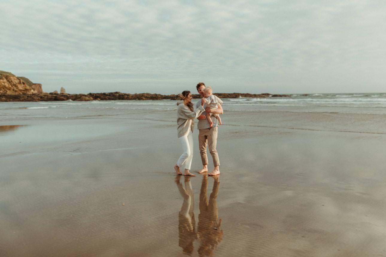 Family standing on the beach laughing together during thier sunset family photography session.