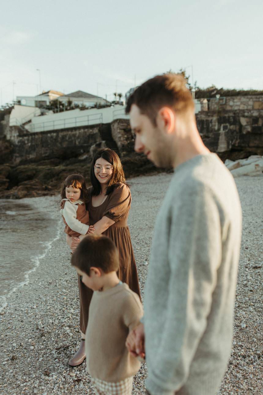 A mother looking at her family wile standing next to the sea. Taken by Melanie Grace, Cornwall family photographer
