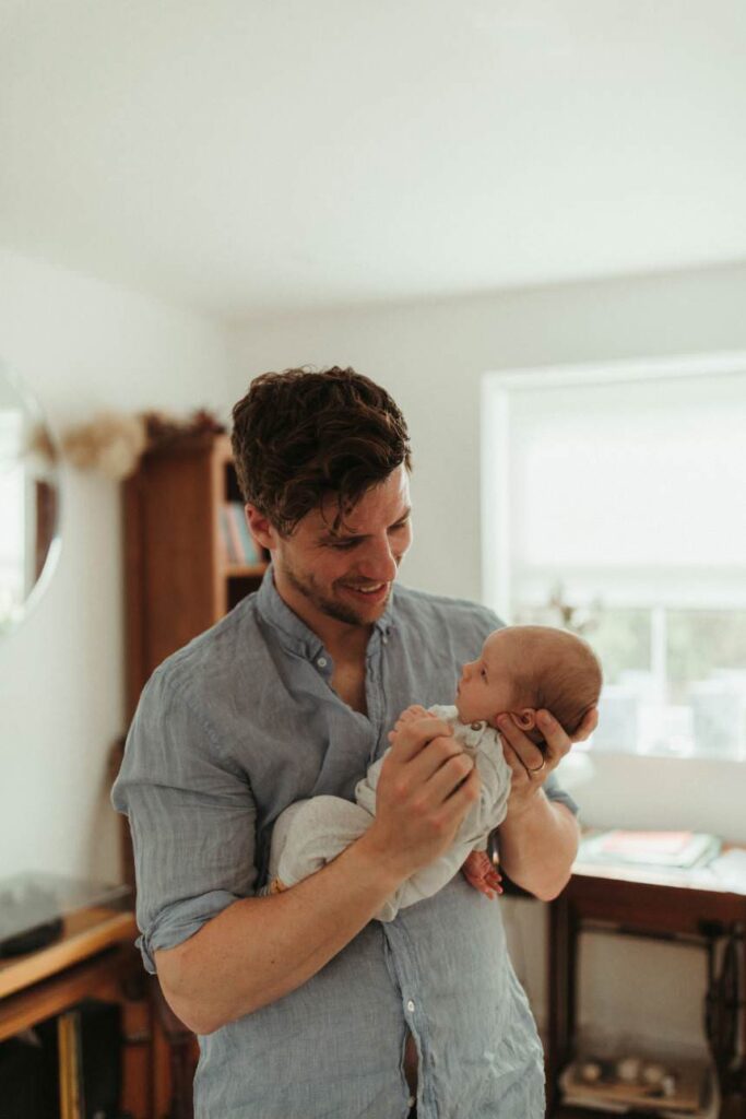 In-home newborn photography session with baby held by parent in St Agnes Cornwall