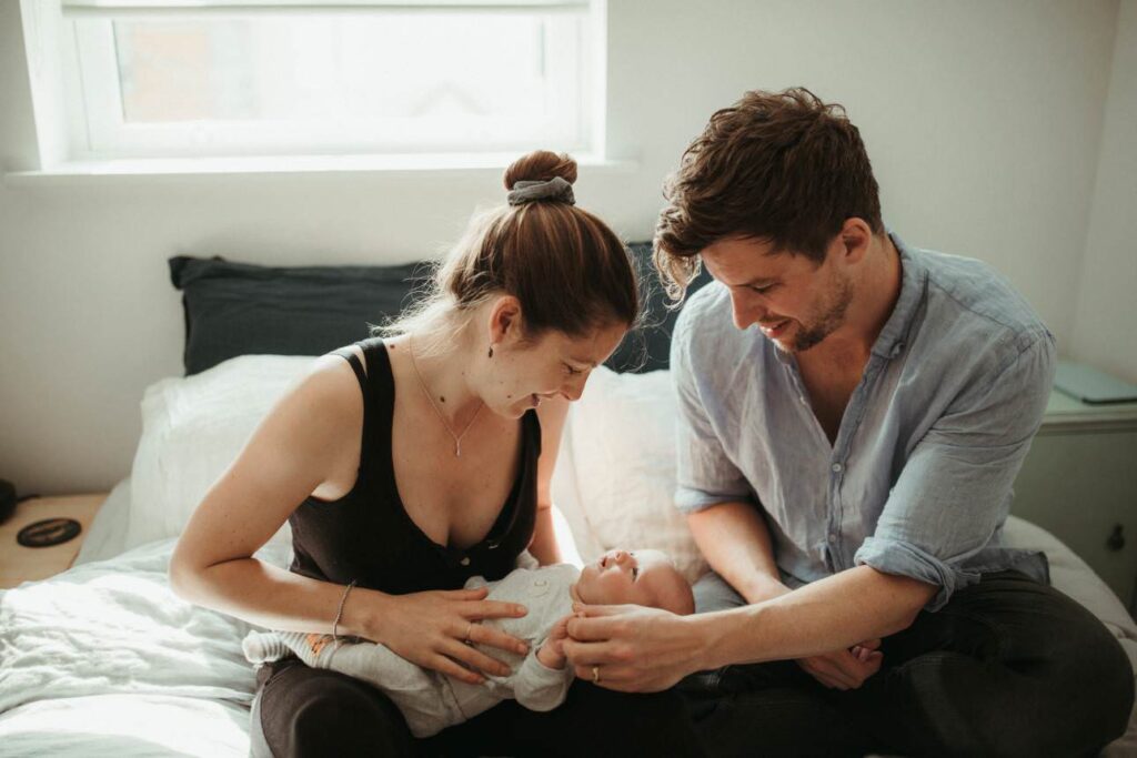In-home newborn photographer session with baby held by parent in Cornwall