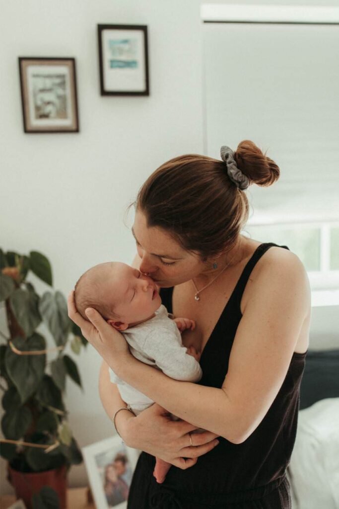 mother softly kissing her newborn baby