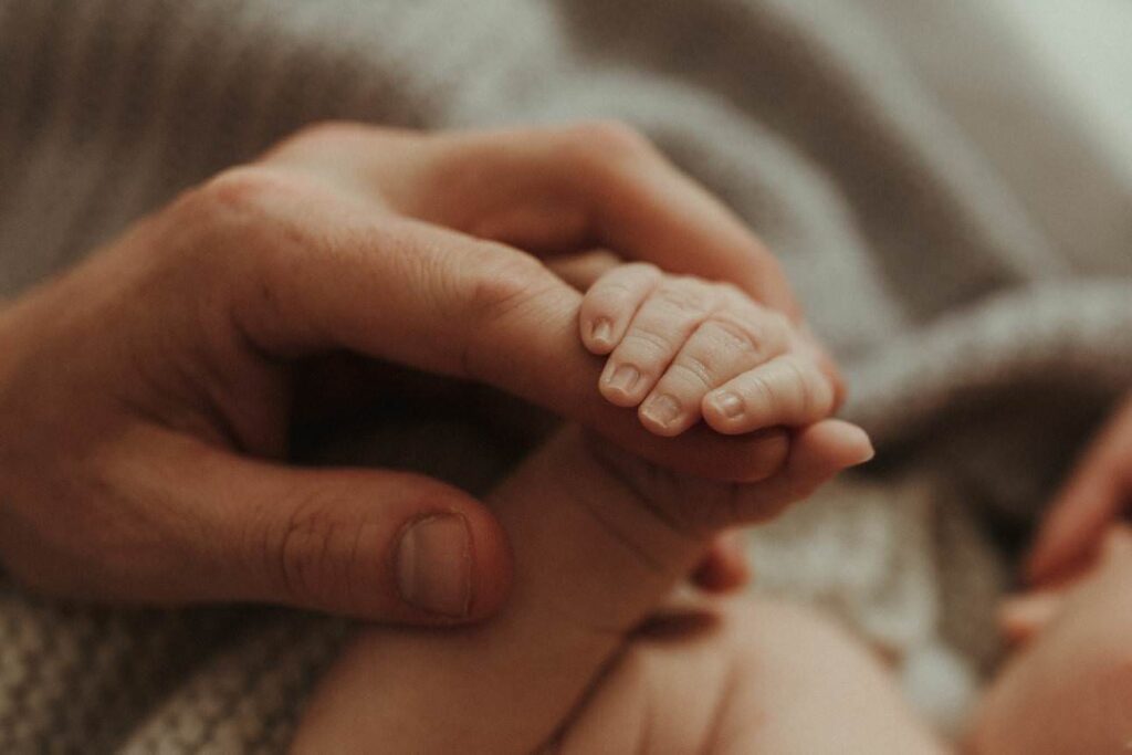 Parent holding baby’s tiny hands