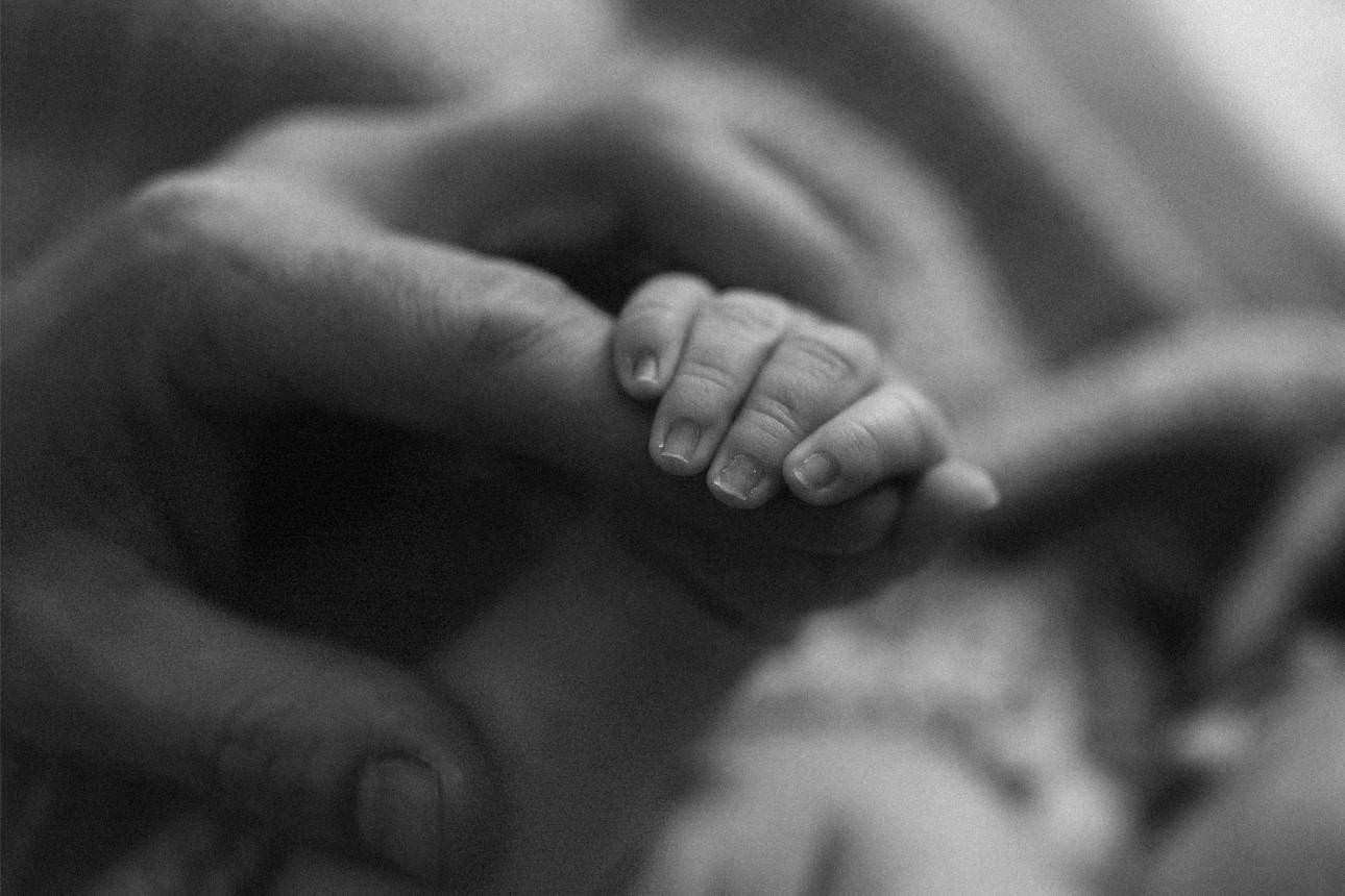 Parent holding newborn baby’s tiny hands