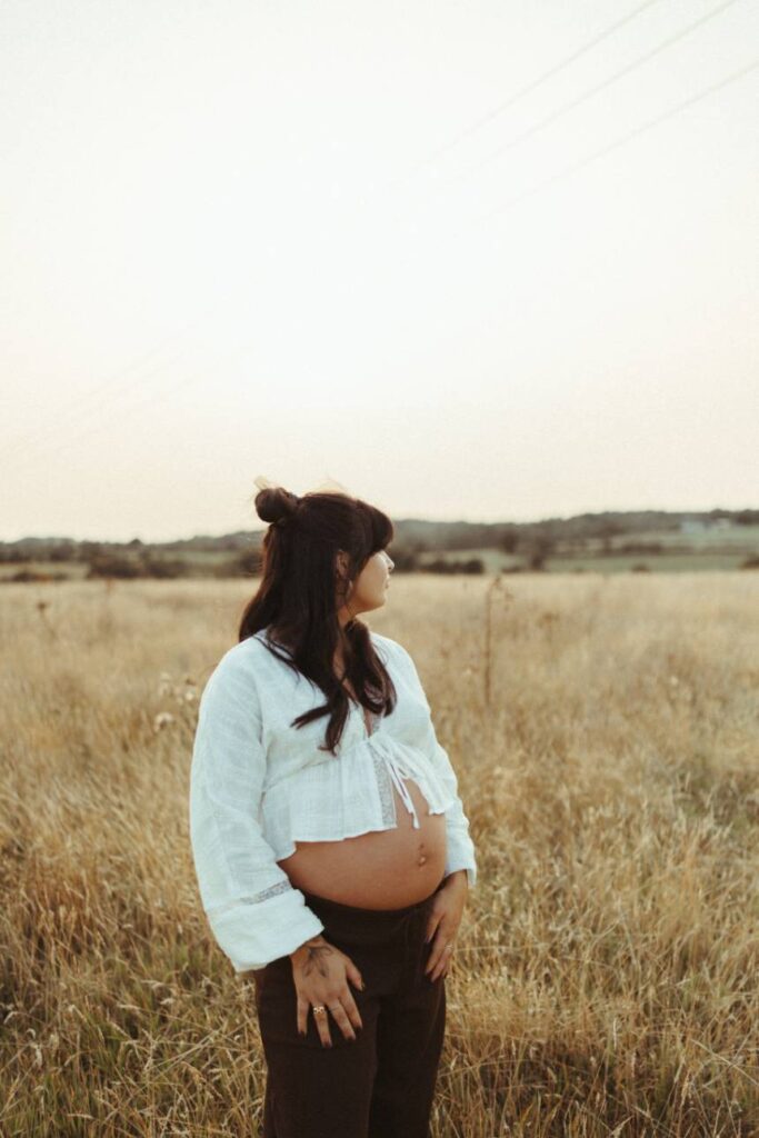 Pregnant woman standing in a meadow in Falmouth
