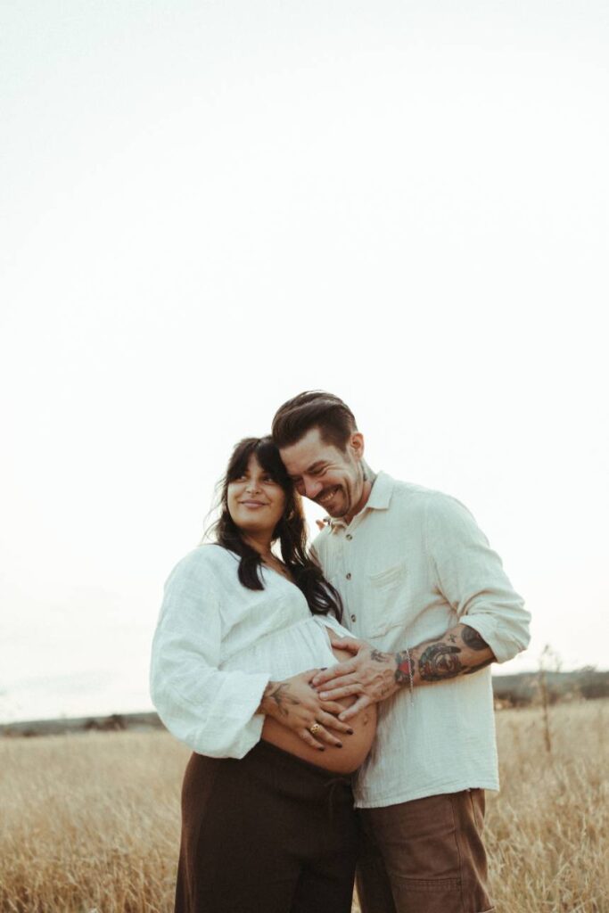 Couple laughing during sunset maternity photoshoot in Falmouth, Cornwall