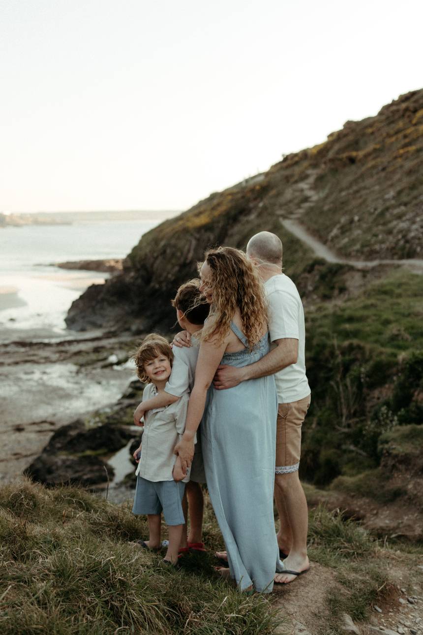 natural lifestyle portrait of family hugging at sunset near Cornwall cliffs