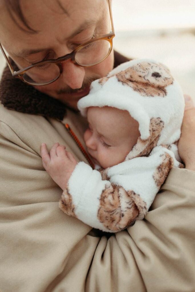 Father holding his sleeping newborn baby on the beach