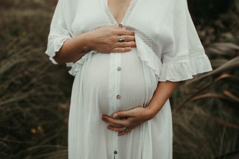 Close up of baby bump with a boho white dress