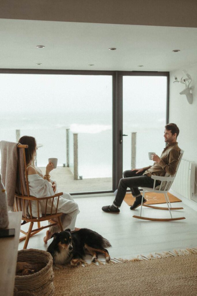 A couple sipping coffee, sat in rocking chairs during their pregnancy photoshoot