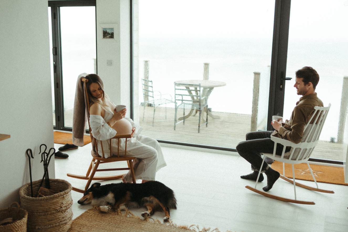 A couple sat together in rocking chairs with the dog laying at their feet