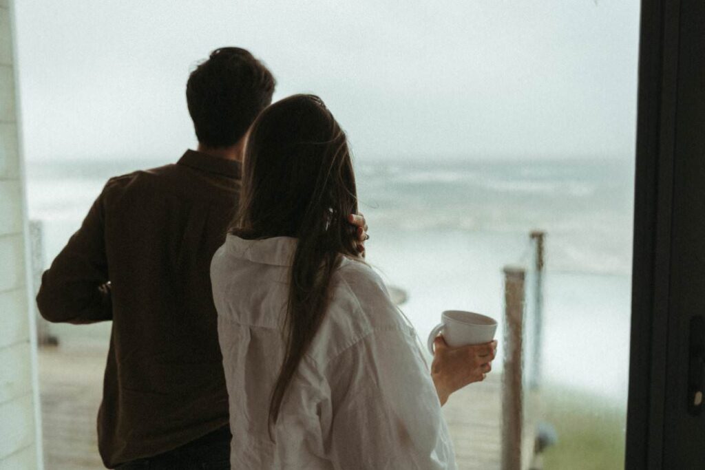 A couple watching the storm from their home during their pregnancy photoshoot in Cornwall