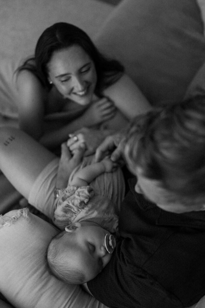 At-home baby photography in Newquay showing parents gently holding their newborn