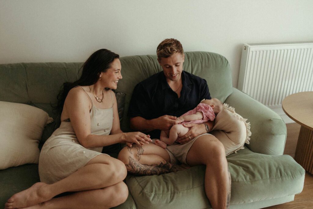 Baby girl lying in parents arms during natural Newquay baby photography session